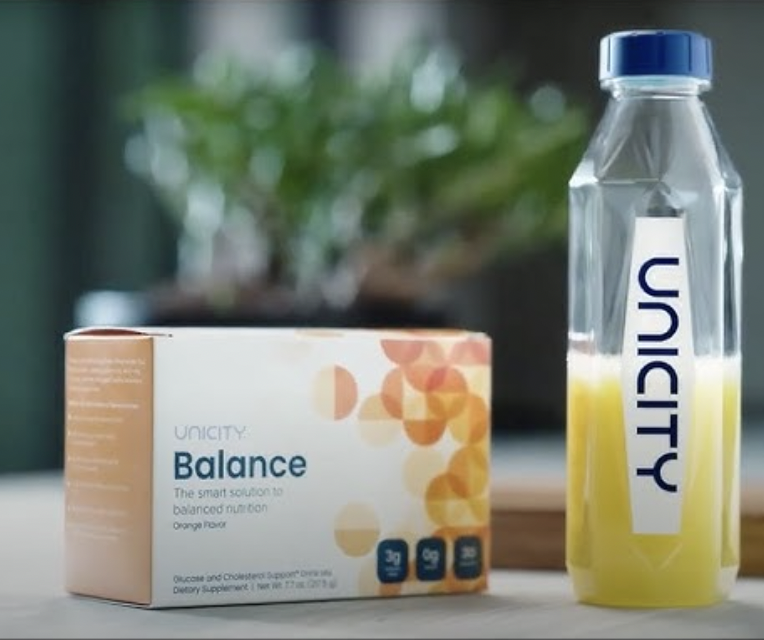 Unicity balance, a box of one months supply of packets next to a unicity diamond bottle containing unicity balance mixed with water. 